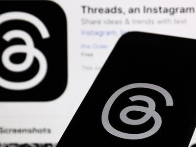 Threads logo displayed on a phone screen and Threads on App Store displayed on a screen in the background in this illustrated photo by Jakub Porzycki with NurPhoto.