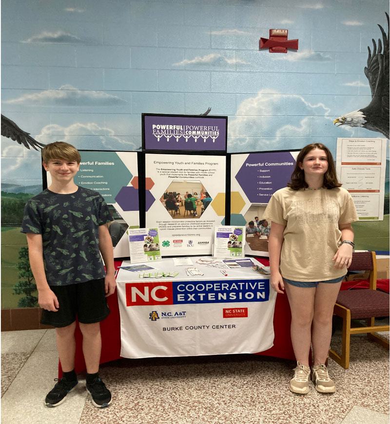 2 youth standing in front of a table
