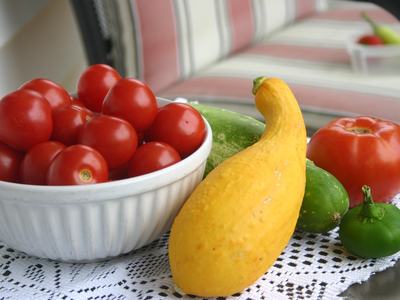 tomatoes in bowl, a squash, pepper, tomato and acucumber on table