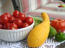 tomatoes in bowl, a squash, pepper, tomato and acucumber on table