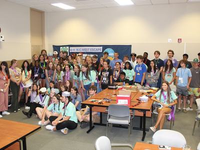 Large group of teens posing in a classroom with banner "4-H N.C. WEST ESCAPE"