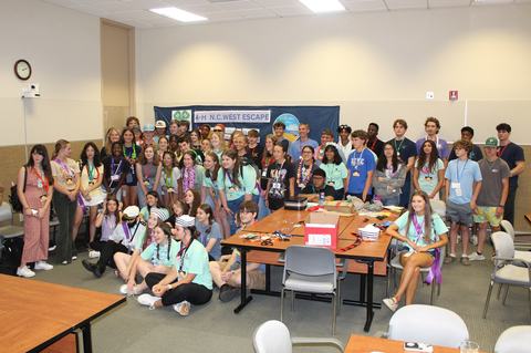 Large group of teens posing in a classroom with banner "4-H N.C. WEST ESCAPE"
