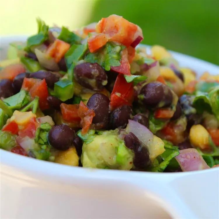 Black bean and corn salad with avocado, diced tomato, red onion, and cilantro in a bowl