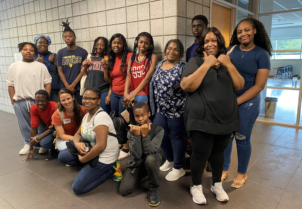 Children and adults pose together in a hallway of a school building.
