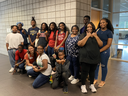Group of adults and children posing together in a tiled school hallway