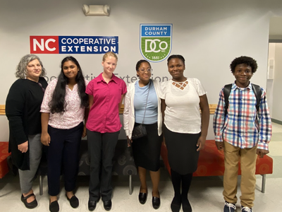 Six people standing under signs reading "NC Cooperative Extension" and "Durham County"