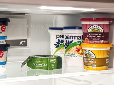 Refrigerator shelf with tubs labeled "Medium Fat Cream Cheese" and fruit yoghurt