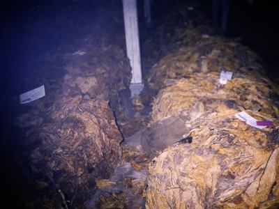 Bales of dried tobacco leaves stacked in storage with paper tags attached