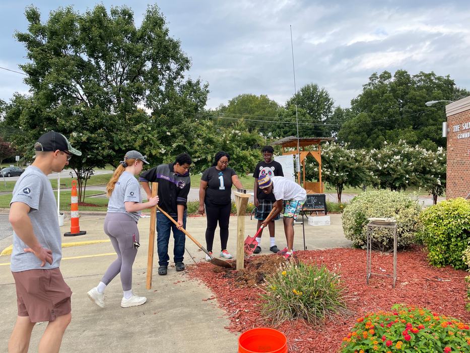 youth workers put in a wooden post with shovels