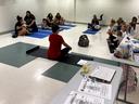 Instructor seated on yoga mat leading parents with infants and toddlers on mats in a classroom