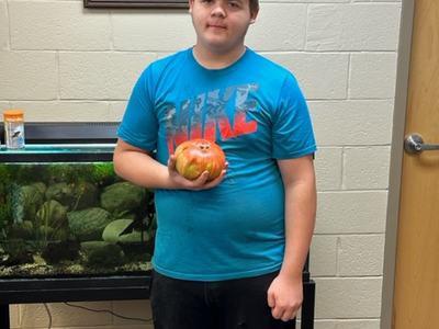 Youth participant holding his giant tomato