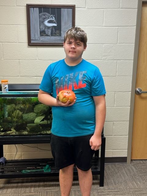 Youth participant holding his big tomato for the contest