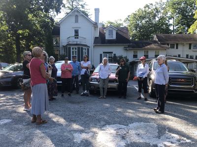 Group of adults standing in a parking lot in front of a white multi-story house