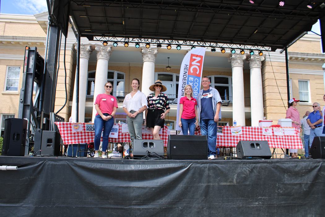 Five adults standing together on a stage. 