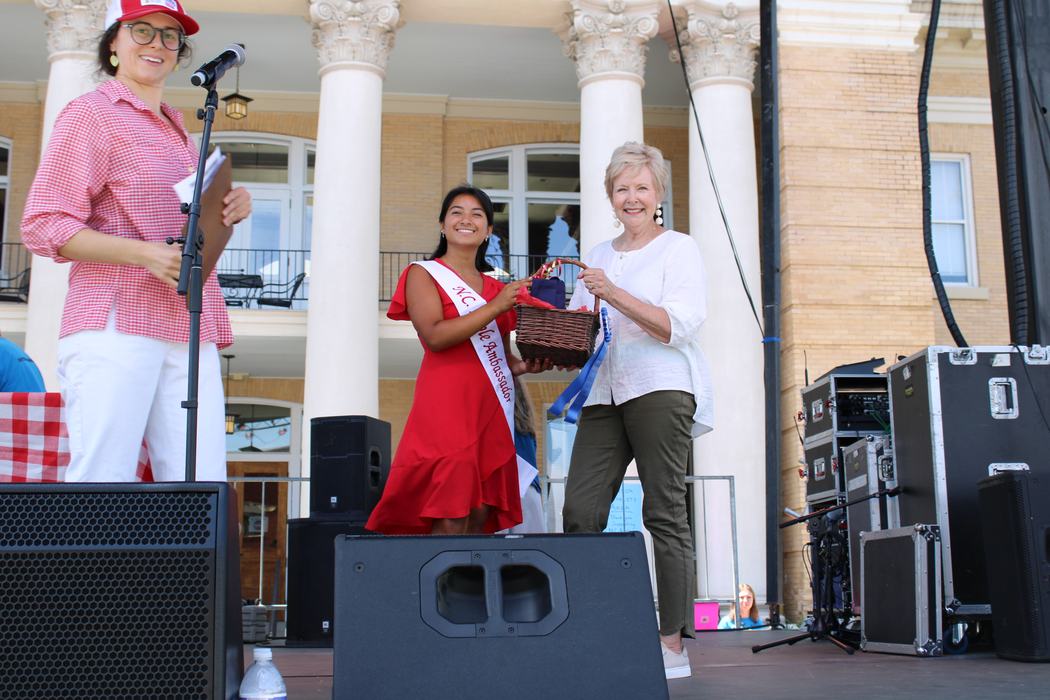 Woman on the left handing gift basket to woman on the right. 