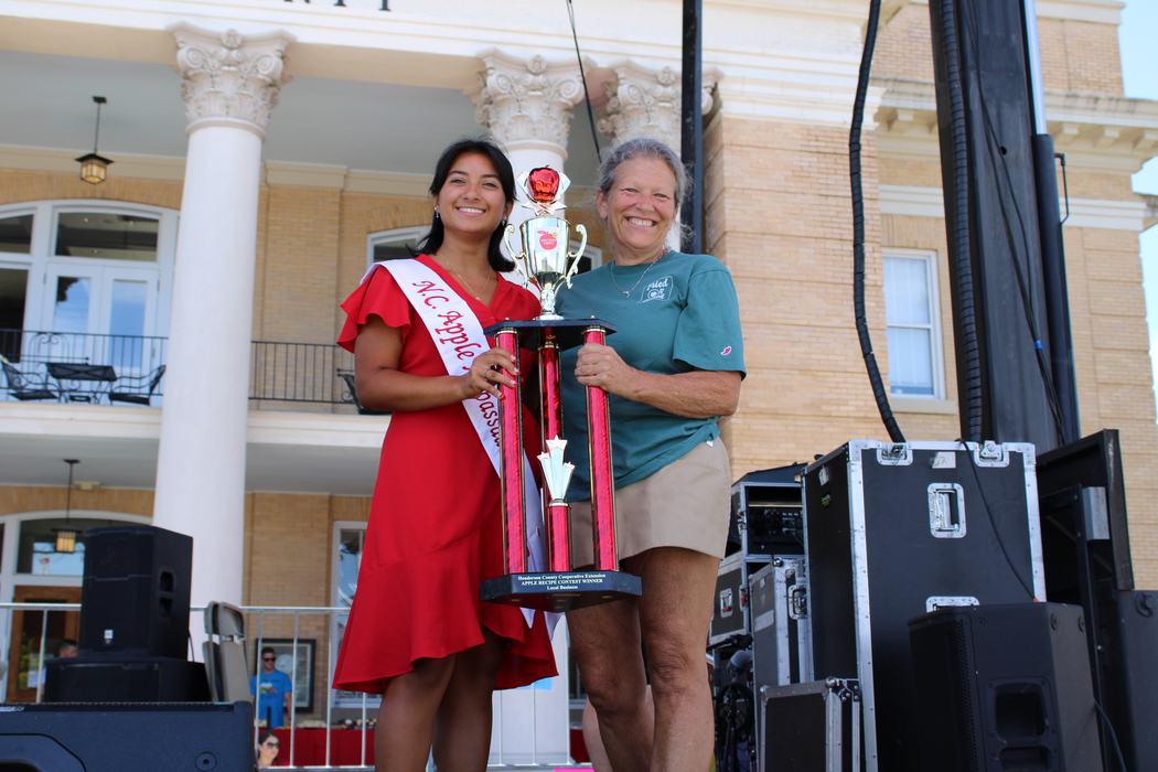 Woman on the left handing trophy to woman on the right. 