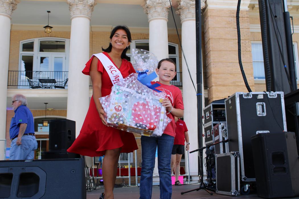 Woman on the left handing gift basket to a female child on the right. 