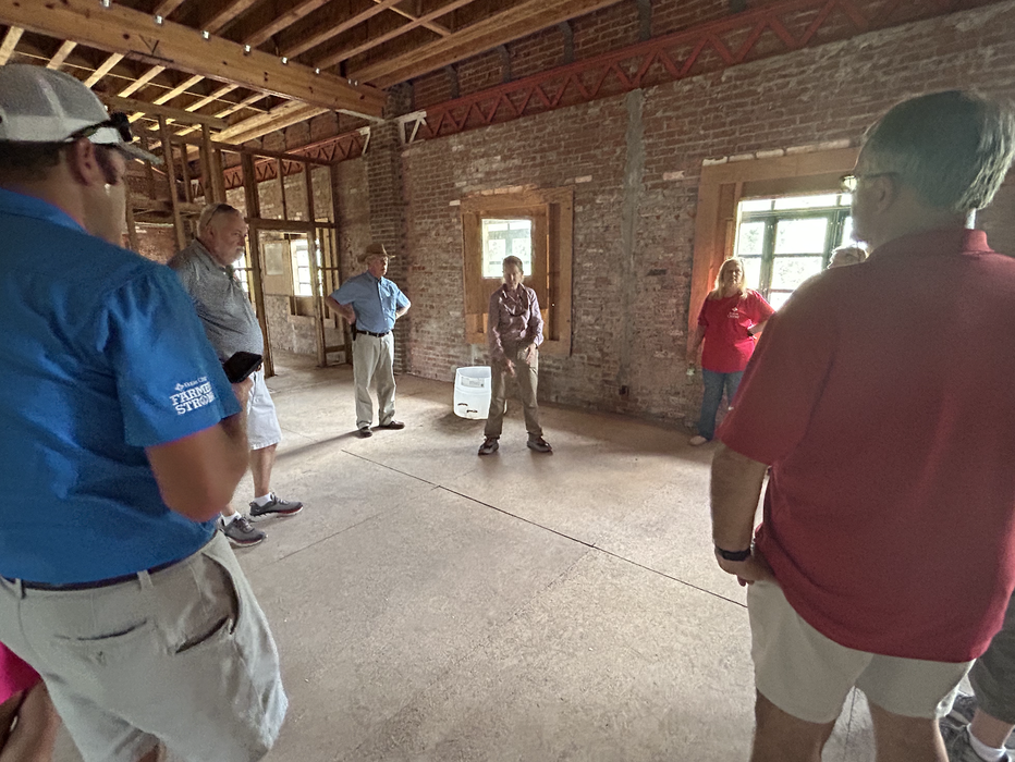 Group of people standing in an empty brick interior around a central person.
