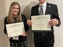 two teens in professional clothing hold award certificates