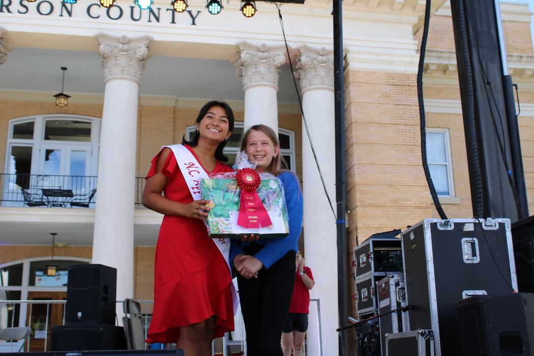 Woman on the left handing gift basket to a female child on the right. 