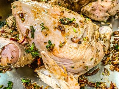 Raw herb- and garlic-marinated whole chickens in a metal roasting pan