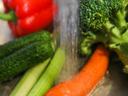 Carrot, broccoli, red bell pepper, cucumber and green onion being rinsed under running water.