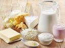 Assorted dairy products: milk jug, butter, cheeses, yogurt, cottage cheese, pink yogurt drink.