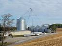 Grain elevators and metal silos with trucks parked at a rural farm facility