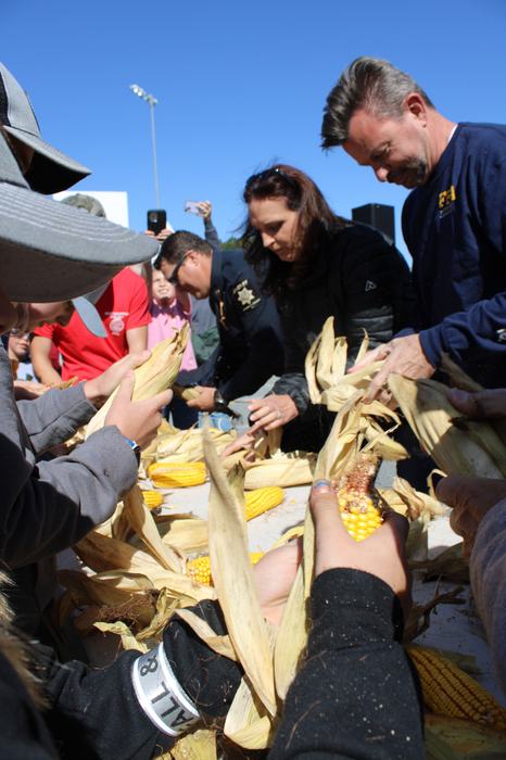 Children and adults compete in a corn shucking competition. 