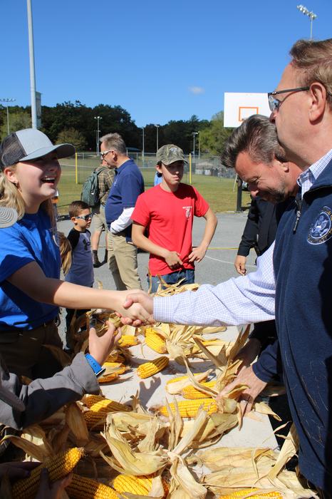 A girl is congratulated for her participation in a corn shucking competition.