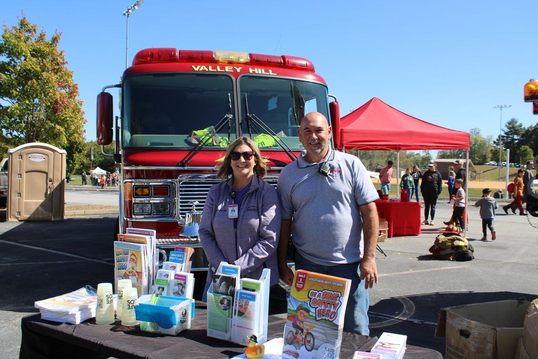 Two people pose in front of a firetruck. 