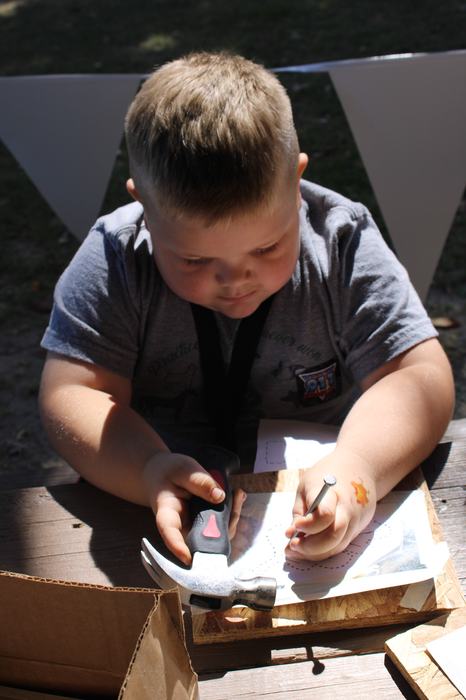 A child uses a hammer and nail.