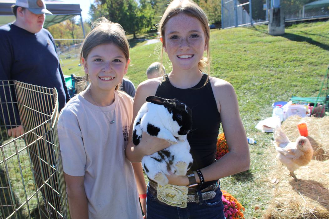 Two children pose with a black and white rabbit.