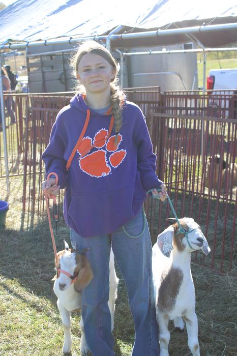 A girl poses with two goats.