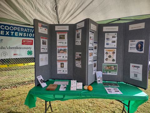NC Cooperative Extension booth with display panels, brochures, and two small pumpkins
