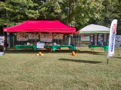 Outdoor event tents with tables, 4-H club displays and NC Cooperative Extension banner