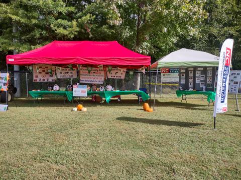 Outdoor event tents with tables, 4-H club displays and NC Cooperative Extension banner