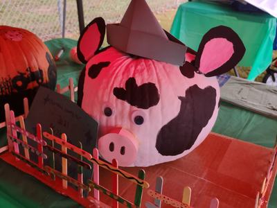 Painted pumpkin decorated as a spotted pig with paper hat, snout, and googly eyes
