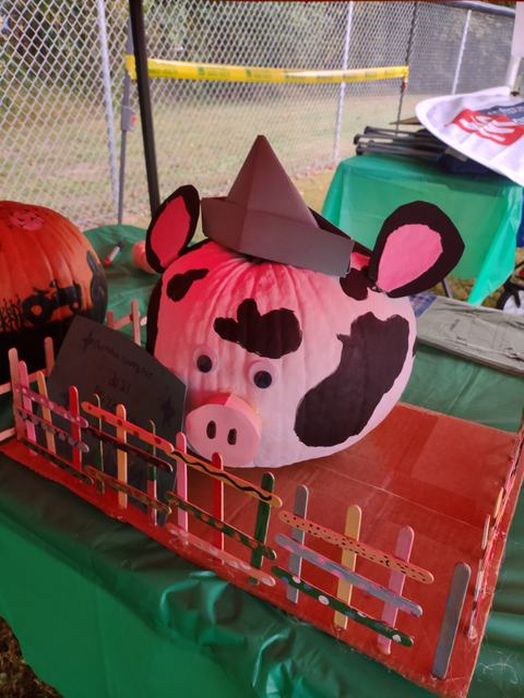 Painted pumpkin decorated as a spotted pig with paper hat, snout, and googly eyes