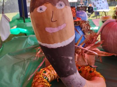 Painted gourd decorated with a painted face and beads on a green table at a fair tent