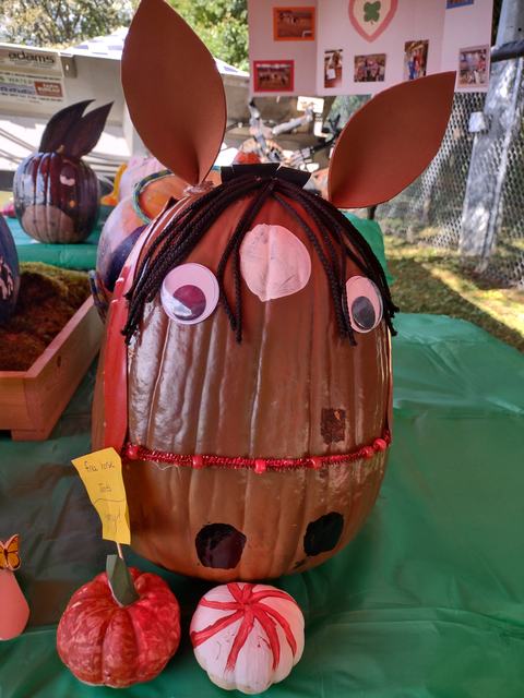 Decorated pumpkin with googly eyes, yarn hair, cardboard ears and two small painted pumpkins