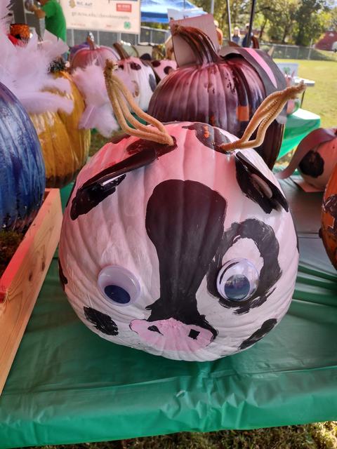 Painted pumpkin decorated as a cow with googly eyes and pipe-cleaner horns