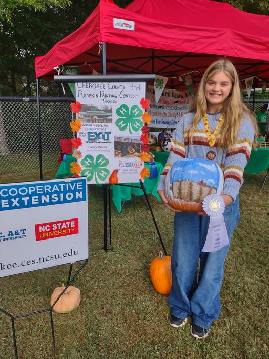 A girl poses with an award winning painted pumpkin.