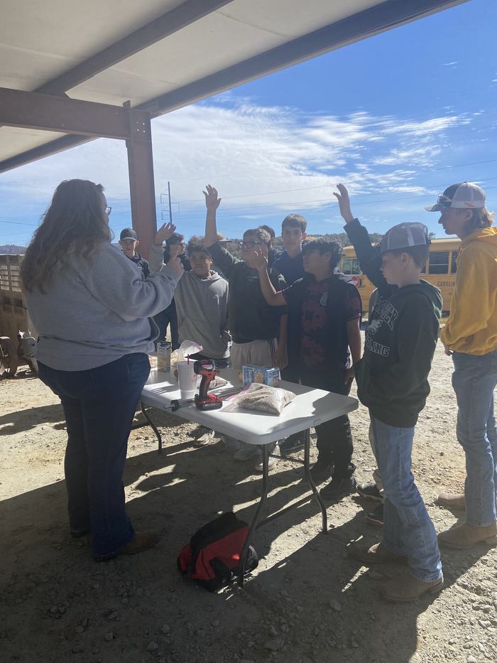 Students raise hands at a table.