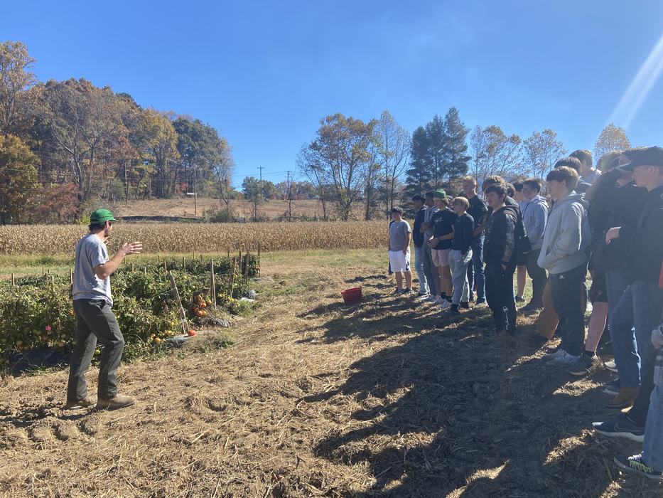 A man gives a lecture in front of crops.