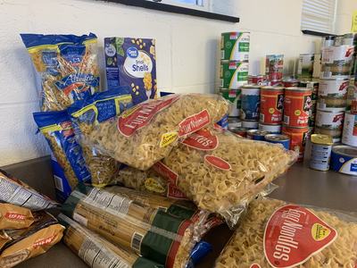 Bags labeled "Egg Noodles" and other pasta beside stacks of canned goods on a countertop