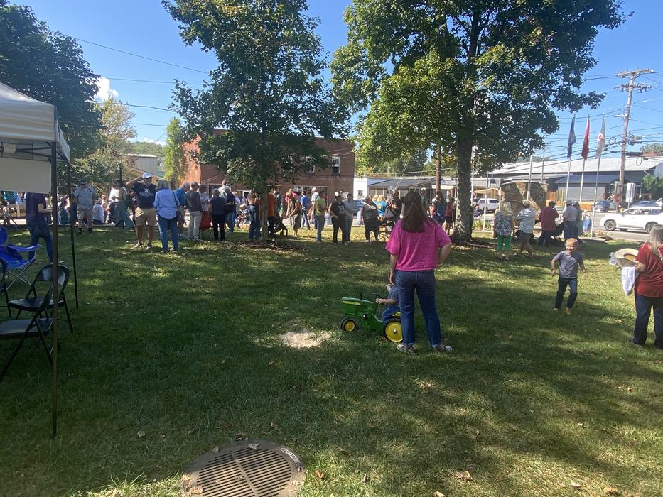 crowd, child rides on tiny play tractor