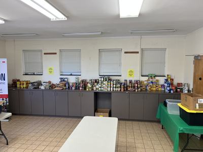 Long counter holding organized canned and boxed food donations in a community room
