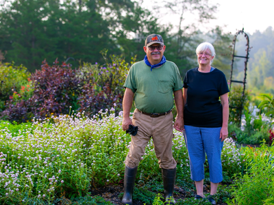Man and woman standing in a flowering garden, holding hands