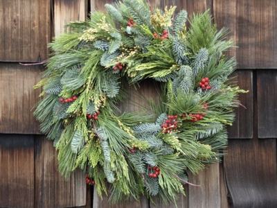 Evergreen pine and fir wreath with red berries hanging on wooden shingle wall